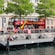 A double decker bus with the words ‘City Sightseeing Copenhagen’ parked on a street with a promenade overlooking the water
